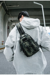 Detail view of a camouflage tactical chest bag with MOLLE webbing and D-rings on street