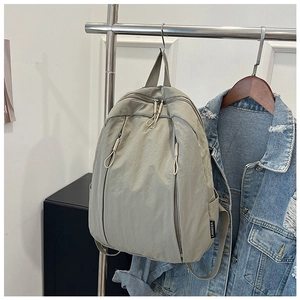 Detailed view of grey-green nylon backpack with multi-zipper pockets and brand label