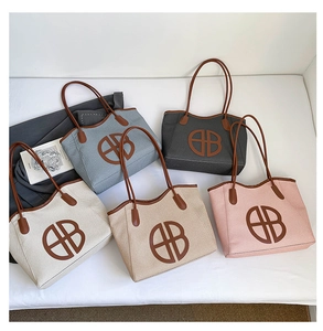 Flat lay of multiple canvas tote bags in various colors with circular BB logo