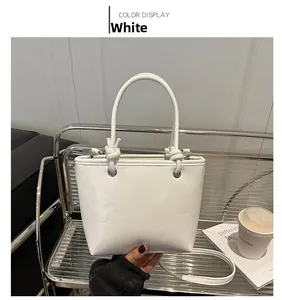 Detail view of white leather tote bag featuring a unique knotted handle and shoulder strap