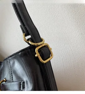 Detail of vintage black leather backpack with polished gold metal hardware and adjustable strap