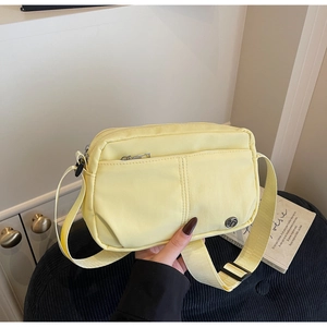 Gros plan détaillé d'un sac bandoulière en nylon jaune clair avec poches zippées multicouches