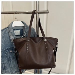 Detailaufnahme der dunkelbraunen Leder-Shopper mit silbernen Stern-Nieten und Metallringen