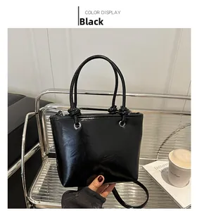 Detail of a black glossy bucket bag with knotted handle on a stylish lifestyle background