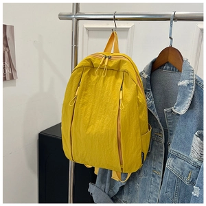 Detail view of bright yellow nylon backpack with textured fabric hanging on a rack