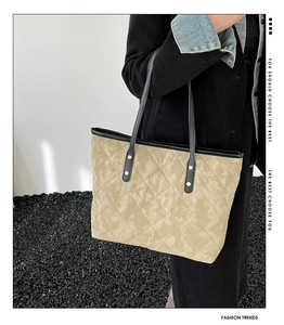 Close-up of quilted tote bag featuring golden rivet details and black slim shoulder straps