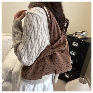 Detailed view of brown corduroy hobo bag with heart patterns and large bow on a model