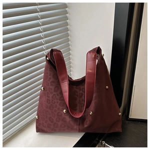 Detail of burgundy leopard print tote bag with matte texture and gold rivet embellishments