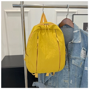 Detail of yellow nylon backpack with water-resistant crinkle texture and dual front zippers