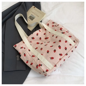 Dettaglio della borsa tote in velluto rosa con stampa fragola e manici in tela