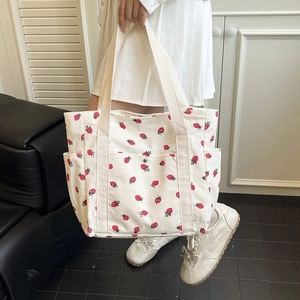 Dettaglio della borsa tote in velluto a coste con motivi a fragola e tasche laterali