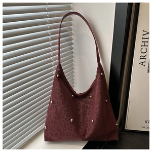 Detail of burgundy leopard embossed shoulder bag with gold metal rivet accents