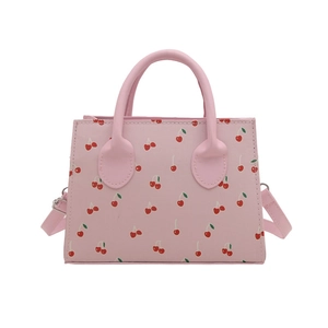 Pink crossbody bag with cherry prints and top handle on a clean white background