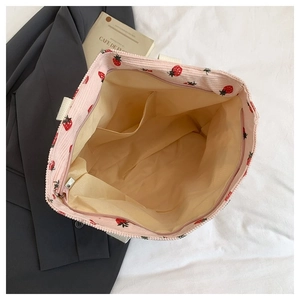 Dettaglio interno della borsa tote in velluto rosa con tasche multiple e ricamo a fragola