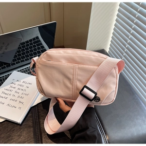 Détail du sac à bandoulière en toile rose clair avec sangle réglable et poche zippée