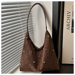 Close-up of leopard print faux suede handbag with gold rivet studs and leather strap