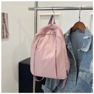 Detail of light pink minimalist backpack with nylon texture and side brand tag on a hanger