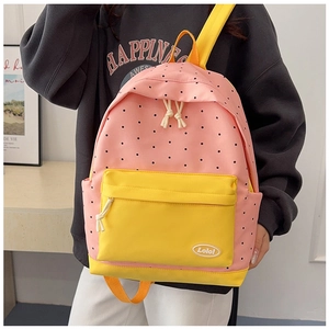 Detailed side view of a pink polka dot and yellow color-block backpack on a model