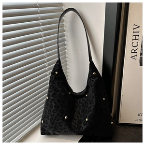 Detailed close-up of leopard print hobo bag with golden stud rivets and black shoulder strap