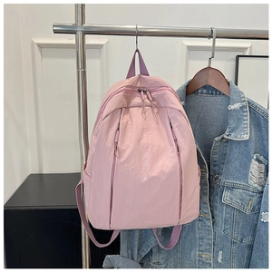 Pink nylon backpack detail showing durable zippers and side pockets on a metal rack