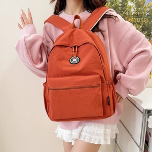 Minimalist brick red canvas backpack for school and commute worn by a model