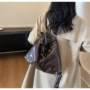 Detailed back view of a dark brown vintage leather backpack on a model with long straps