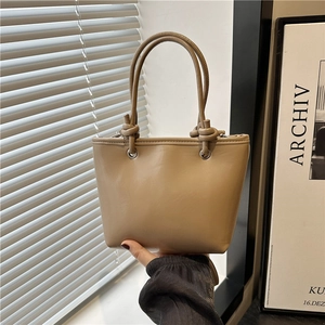Chic beige leather bucket bag with knotted handles, ideal for stylish daily commuting