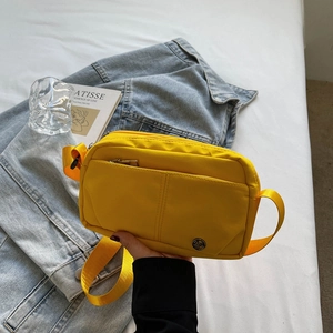 Sac bandoulière en nylon jaune vif minimaliste avec plusieurs poches sur veste denim