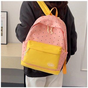 Pink polka dot backpack with yellow zip pocket and Lolo logo in a cozy indoor setting
