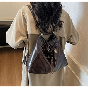 Detail view of a vintage dark brown leather backpack on a model with khaki trench coat