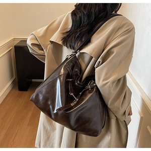 Detail view of large dark brown leather tote bag with glossy finish and side buckle straps