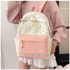 Close-up of cream polka dot backpack with pink pockets and logo detail for students