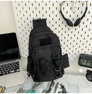 Detail view of black tactical crossbody bag with nylon texture on a white pegboard setup