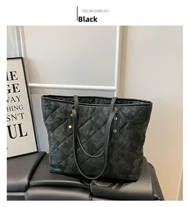 Close-up of black quilted tote bag with diamond stitching and golden metal rivets details