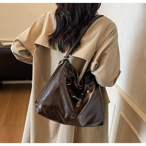 Detail view of large dark brown leather tote bag featuring drawstring and metal ring accents
