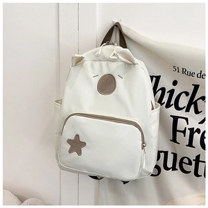 Detailed close-up of cream kids backpack with cute bear embroidery and star patch decor