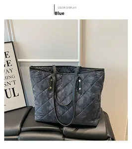 Close-up of blue quilted tote bag detail with black leather straps and gold rivets