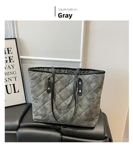 Detail view of grey quilted tote bag with diamond stitching and black leather handles