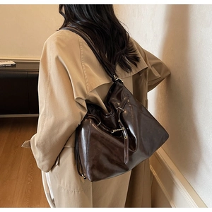 Close-up of vintage brown leather tote bag featuring gold metal rings and retro hardware