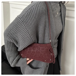 Detail of burgundy leopard print baguette bag with silver studs and bow decoration