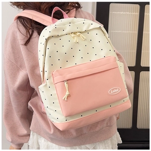 Detail of white polka dot backpack with pink pockets and Lolo badge shown on a model