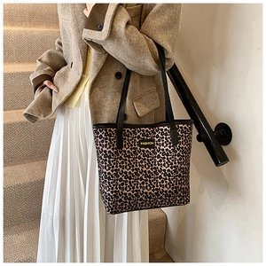 Detail view of leopard print tote bag with black leather straps on fashion model