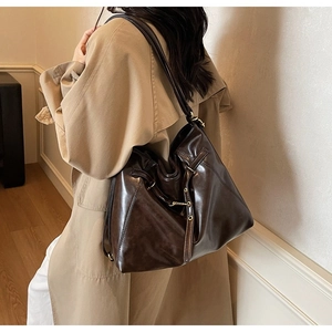 Detail of vintage brown leather tote bag with glossy finish and gold metal hardware