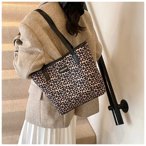Close-up of leopard print tote bag with black leather straps and fashion label detail