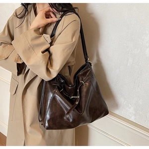 Detailed view of deep brown oily leather hobo tote bag worn with a khaki coat