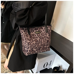 Detail of large leopard print tote bag with black shoulder strap and fashion label