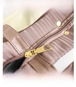 Detail of smooth gold zipper and quilted dusty pink faux leather texture on tote bag