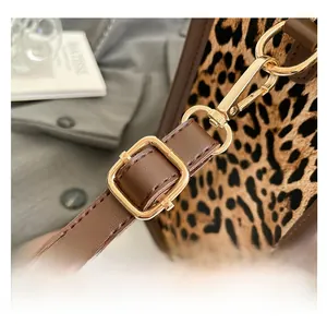 Detail of leopard print bag featuring a brown adjustable strap and gold metal hardware