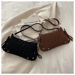 Detail view of leopard print shoulder bags with rivets and side laces on a suit jacket