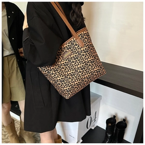 Close-up of leopard print tote bag with brown straps and fashion logo detail